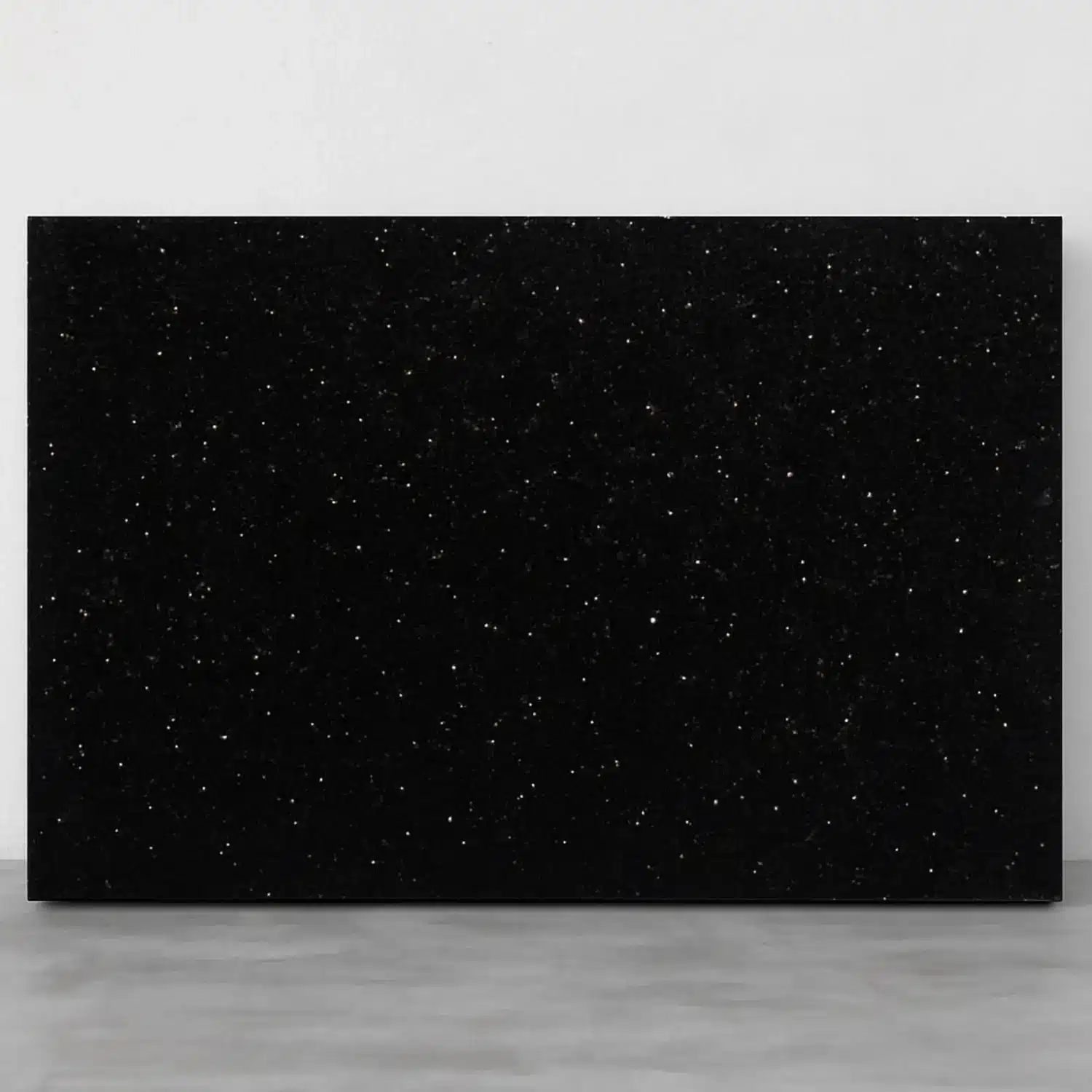 a slab of black galaxy granite placed against a wall
