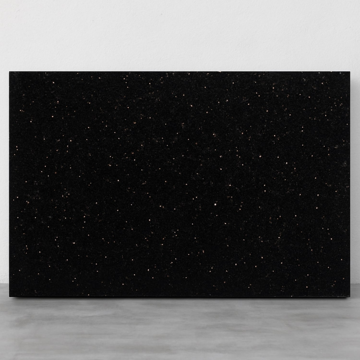 a slab of black galaxy granite placed against a wall